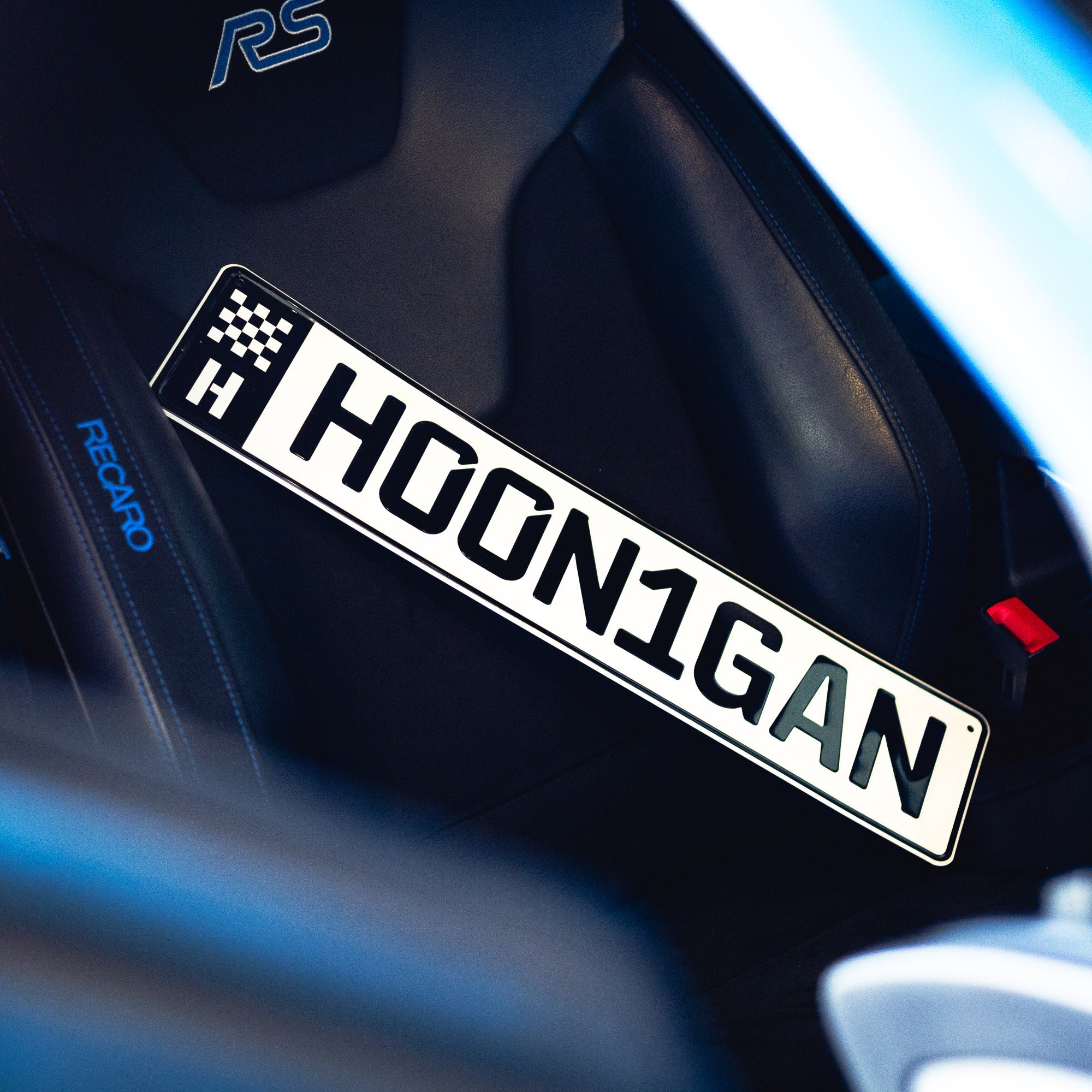Hoonigan EURO license plate displayed on a car seat, showcasing bold lettering and racing-inspired design.