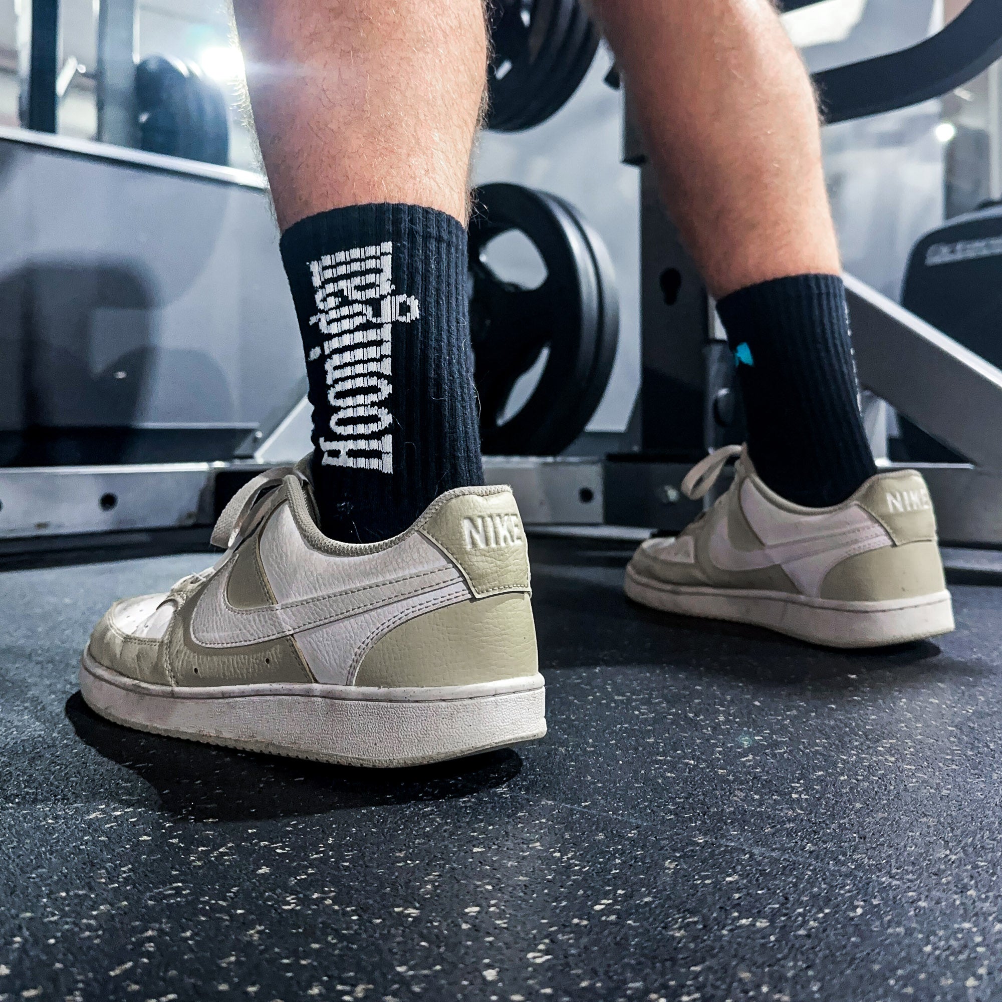 Hoonigan BURNOUT TEAM socks displayed on a person's feet in a gym setting, showcasing a sporty and stylish design.