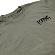 KMC logo short sleeve tee in navy blue with white branding, displayed on a flat surface.