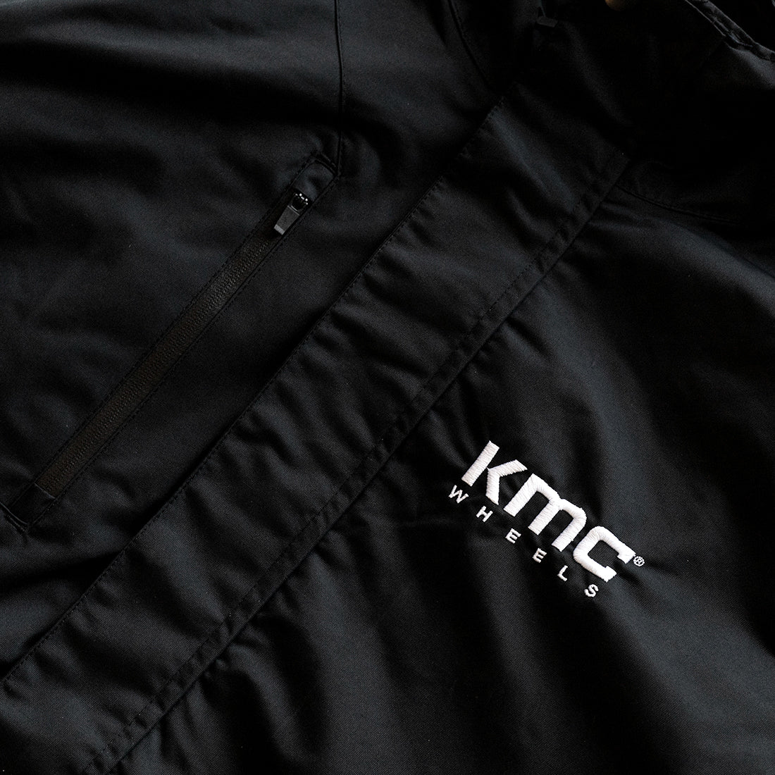 KMC Jacket featuring a sleek black design with a high collar and zippered front, suitable for both outdoor and casual wear.