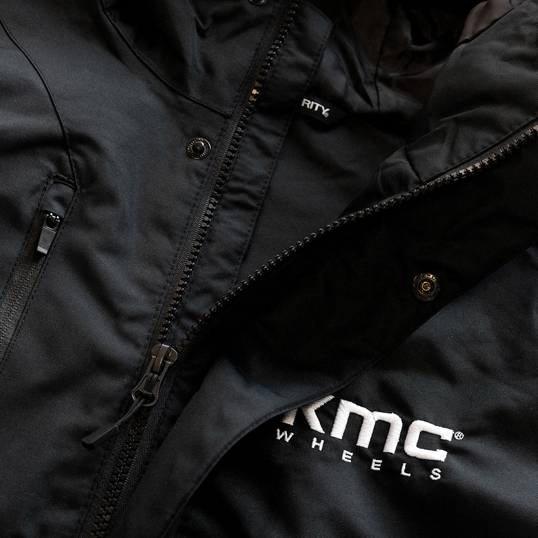 Black KMC jacket featuring a sleek design with a zippered front, adjustable cuffs, and a high collar, perfect for casual wear.