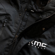 Black KMC jacket featuring a sleek design with a zippered front, adjustable cuffs, and a high collar, perfect for casual wear.
