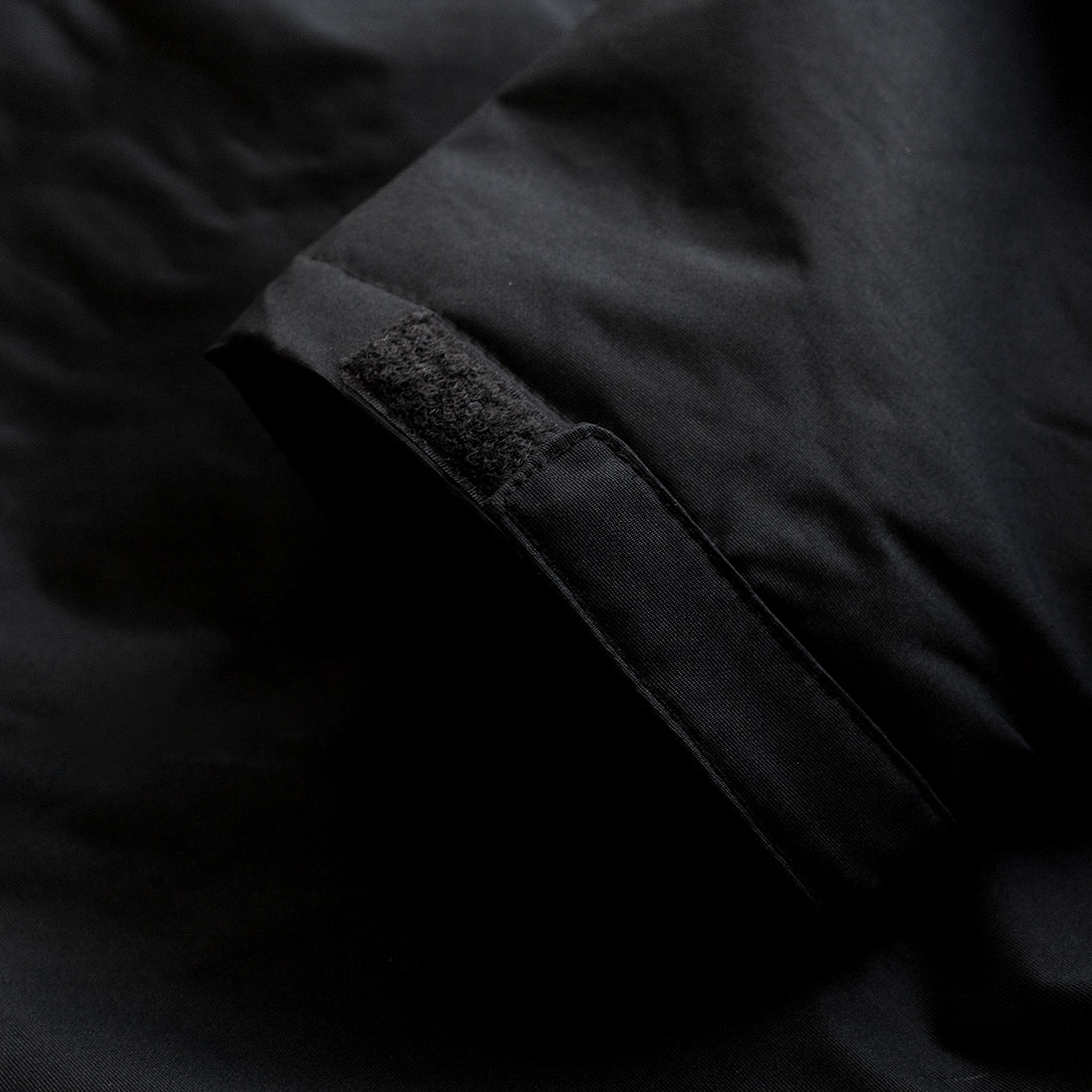 KMC jacket in black featuring a zip front, adjustable hood, and side pockets.