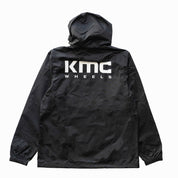 KMC Wheels V2 Half Zip Anorak Jacket in black, featuring a zippered collar, adjustable drawstring hood, and front pocket.