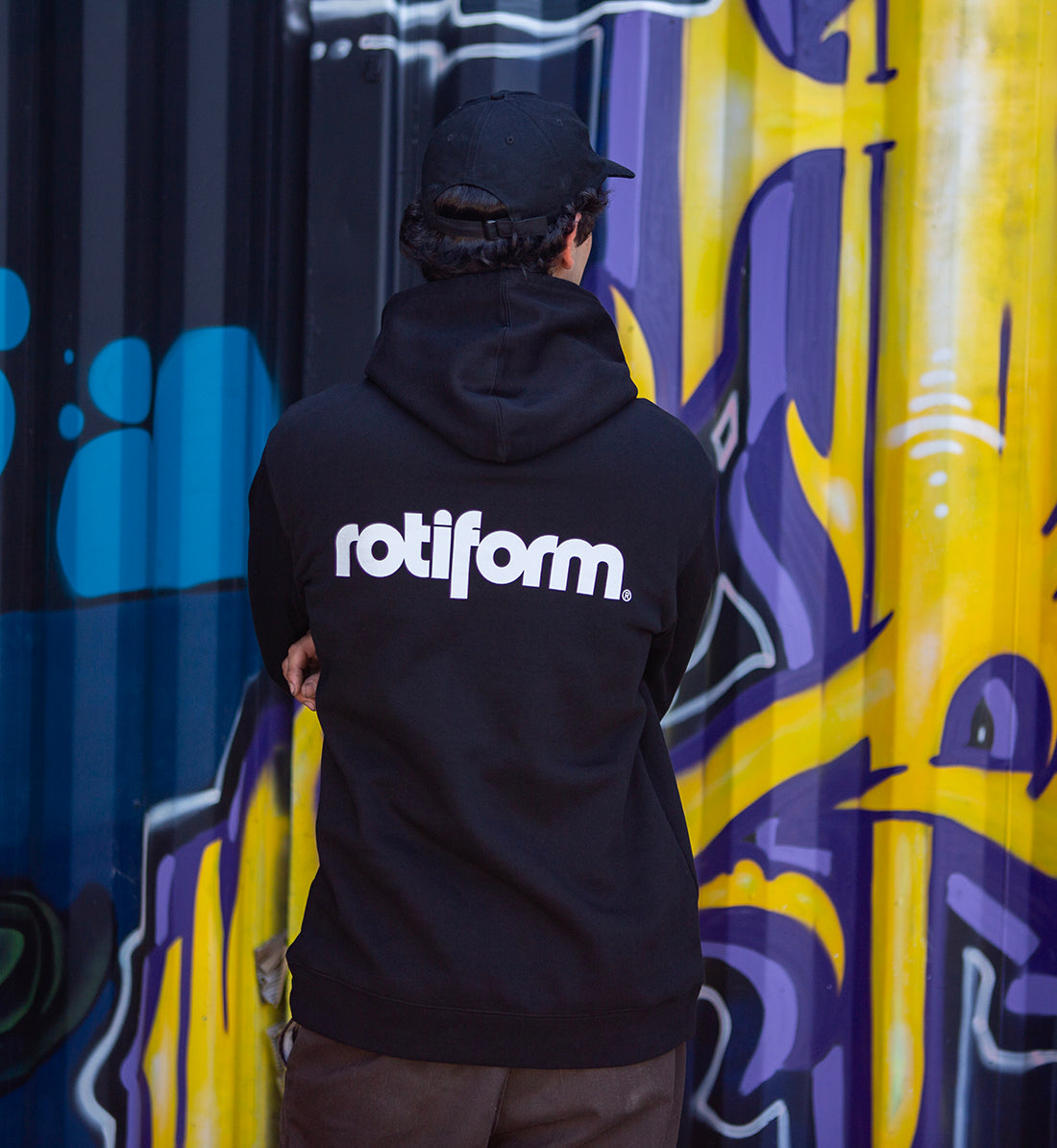 Rotiform STAPLE hoodie in black and white, featuring a prominent Rotiform logo on the back, displayed in a lifestyle setting.