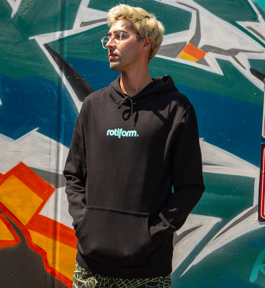Rotiform STAPLE hoodie in black and teal, featuring the Rotiform logo on the front, worn casually in a lifestyle setting.