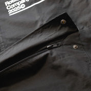 Close-up of the black Rotiform GLOBAL IMPACT Half Zip Anorak Jacket showing a zipper, snap buttons, and fabric details.