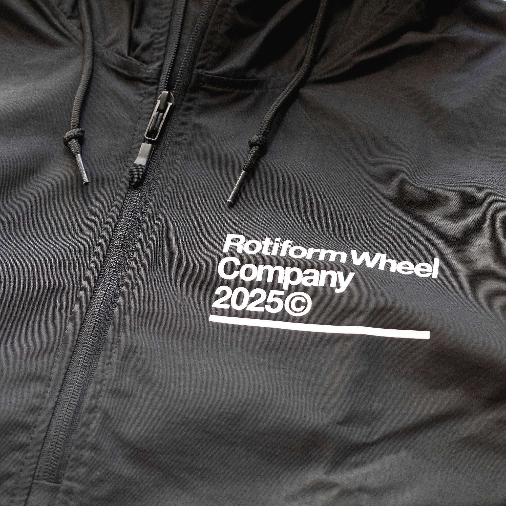 Black Rotiform GLOBAL IMPACT half-zip anorak jacket with white logo text, adjustable drawstrings, and front zipper closure.