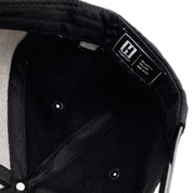 Inside view of a black Hoonigan KB43VER 43i snapback hat with a label indicating 100% acrylic, 20% wool, made in the USA.