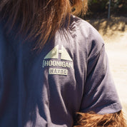 Close-up of a gray Hoonigan TOPOGRAHPHIC TERRAIN short sleeve tee with a logo patch on the shoulder, outdoors in sunlight.