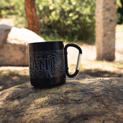 Black mug with topographic map design and the word "GAND" printed on it, featuring a carabiner handle for outdoor use.