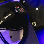 Close-up of a black Hoonigan BRACKET X LOGO snapback hat showing interior labels, branding, and stitching details.