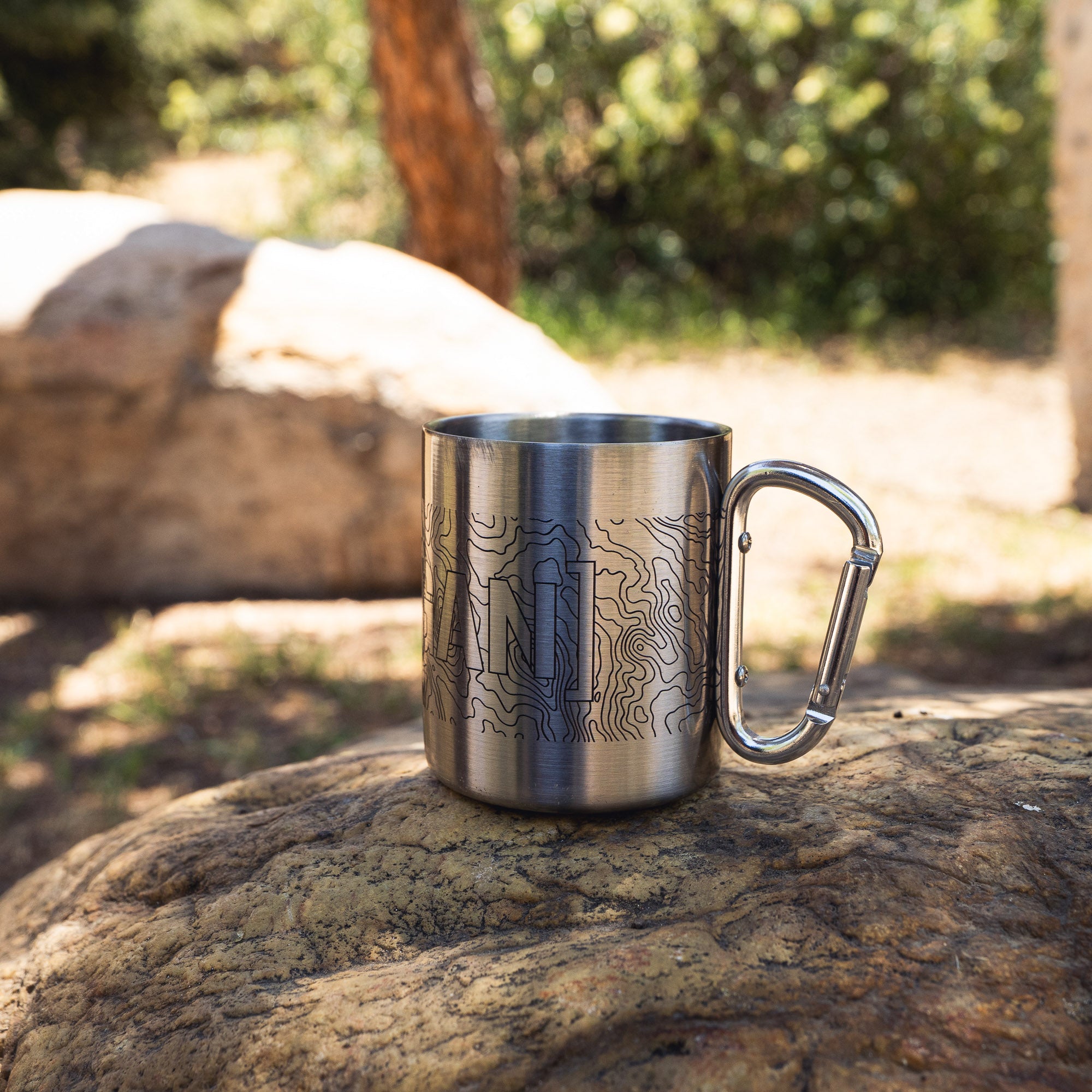 Stainless steel mug with topographic map design and a carabiner handle, ideal for outdoor adventures and camping.