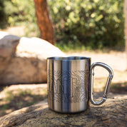 Stainless steel mug with a carabiner handle and topographic design, ideal for outdoor adventures and camping.