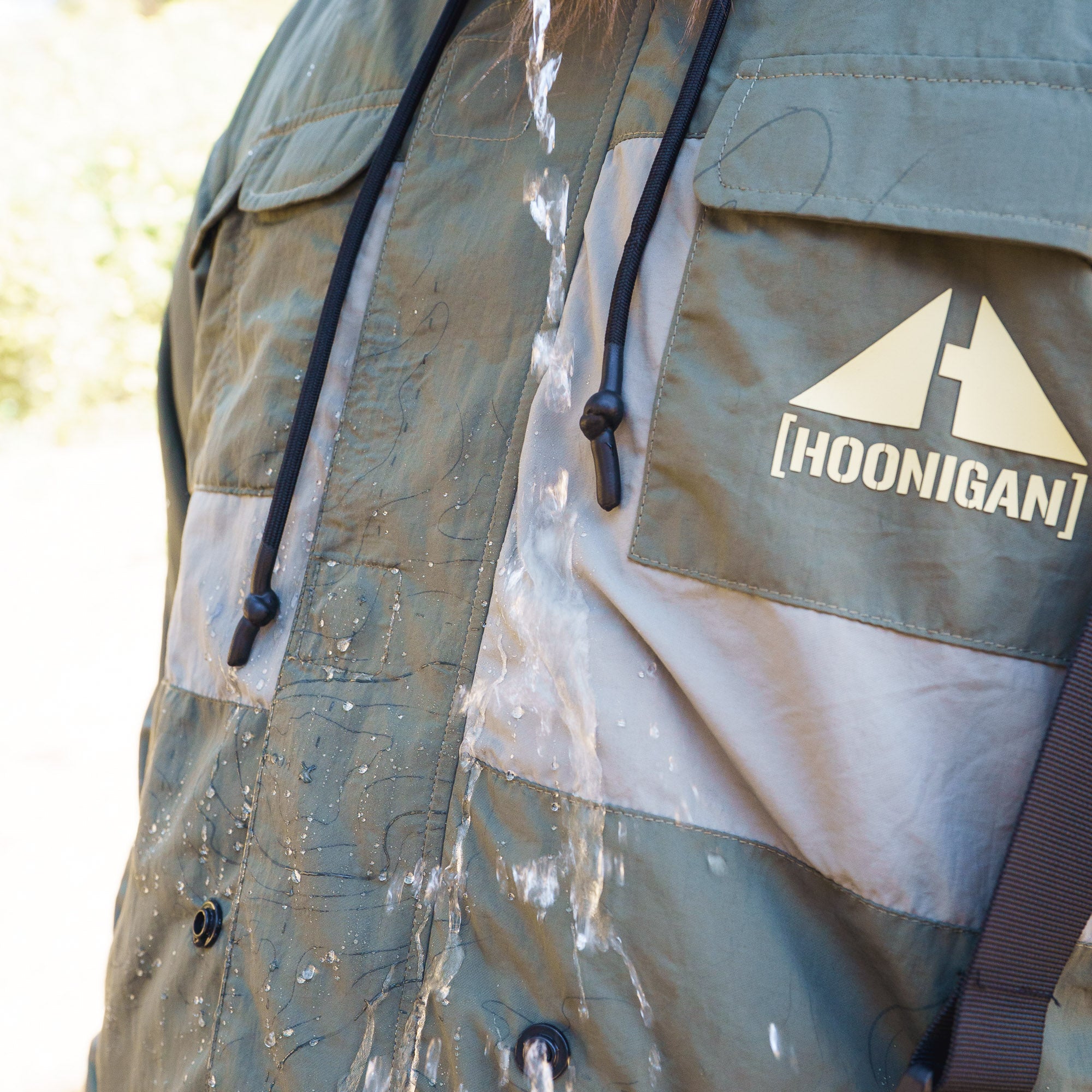 Rain-activated Hoonigan H.A.V.O.C. windbreaker jacket with water-resistant fabric and adjustable drawstrings, shown during rain.