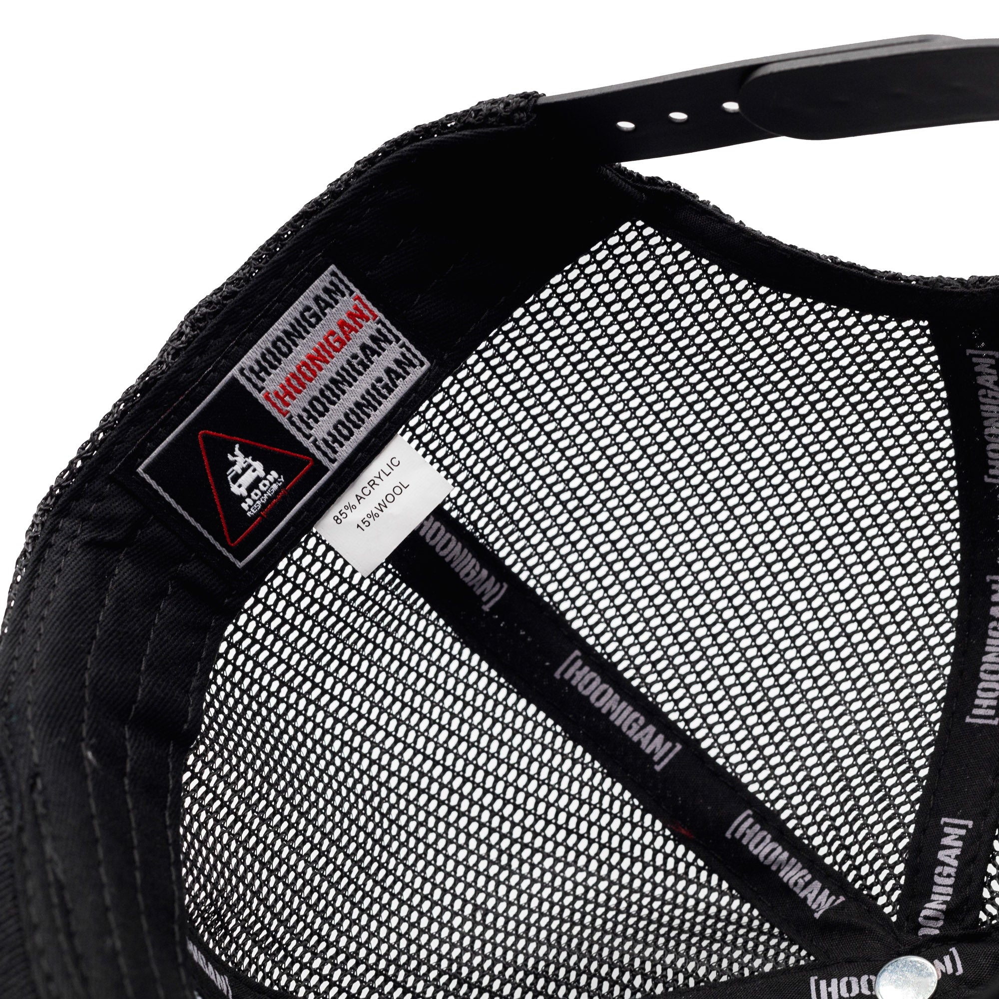 Close-up of the inside of a Hoonigan HITS V2 Trucker Hat showing mesh lining, branding tags, and fabric composition details.