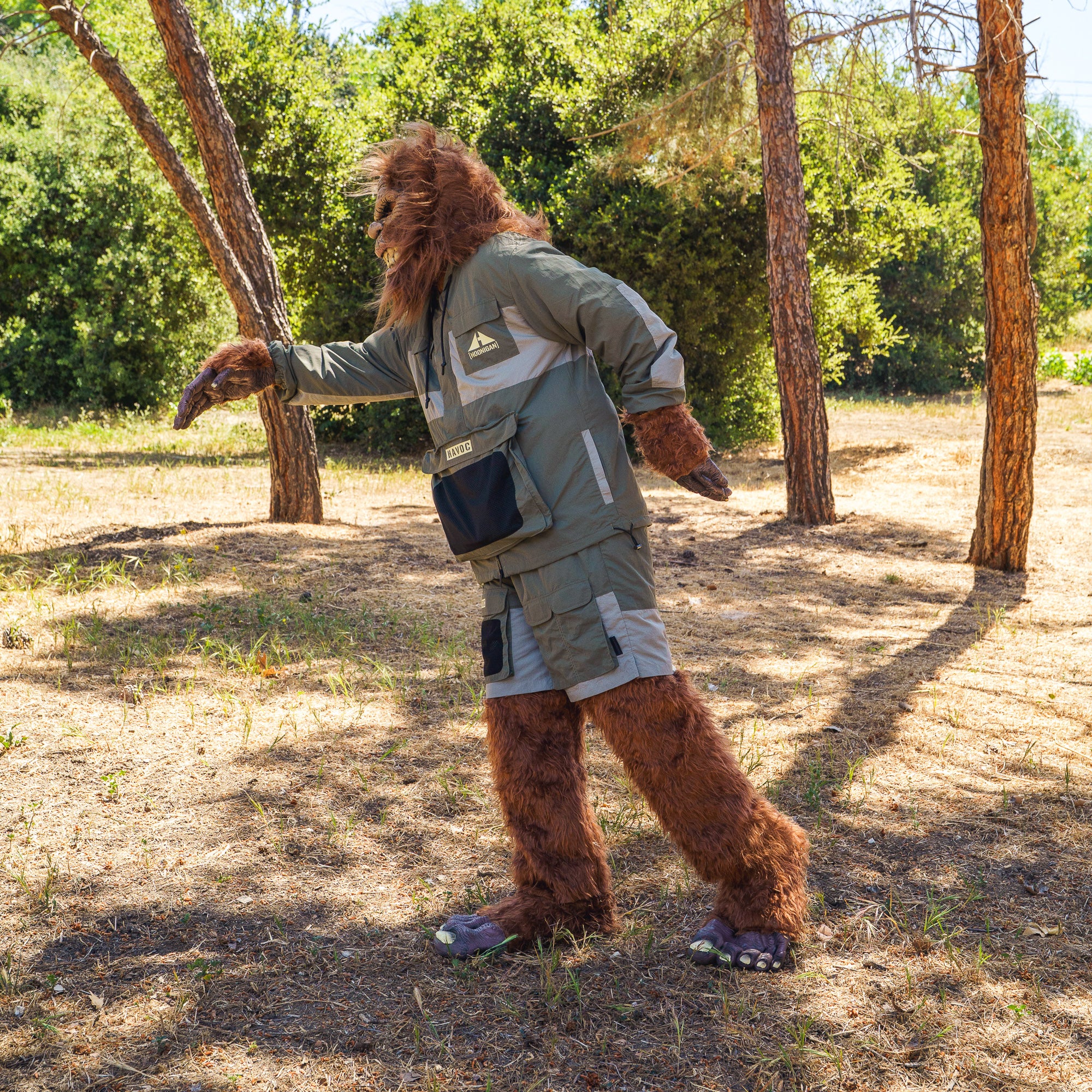 A person in a rain-activated Hoonigan H.A.V.O.C. windbreaker jacket, standing outdoors among trees on a sunny day.