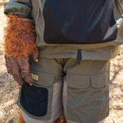 Close-up of khaki cargo shorts with multiple pockets, worn by a person outdoors, featuring rain-activated fabric technology.
