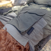 Rain-activated cargo shorts with multiple pockets, shown on a person lying outdoors in a natural setting.
