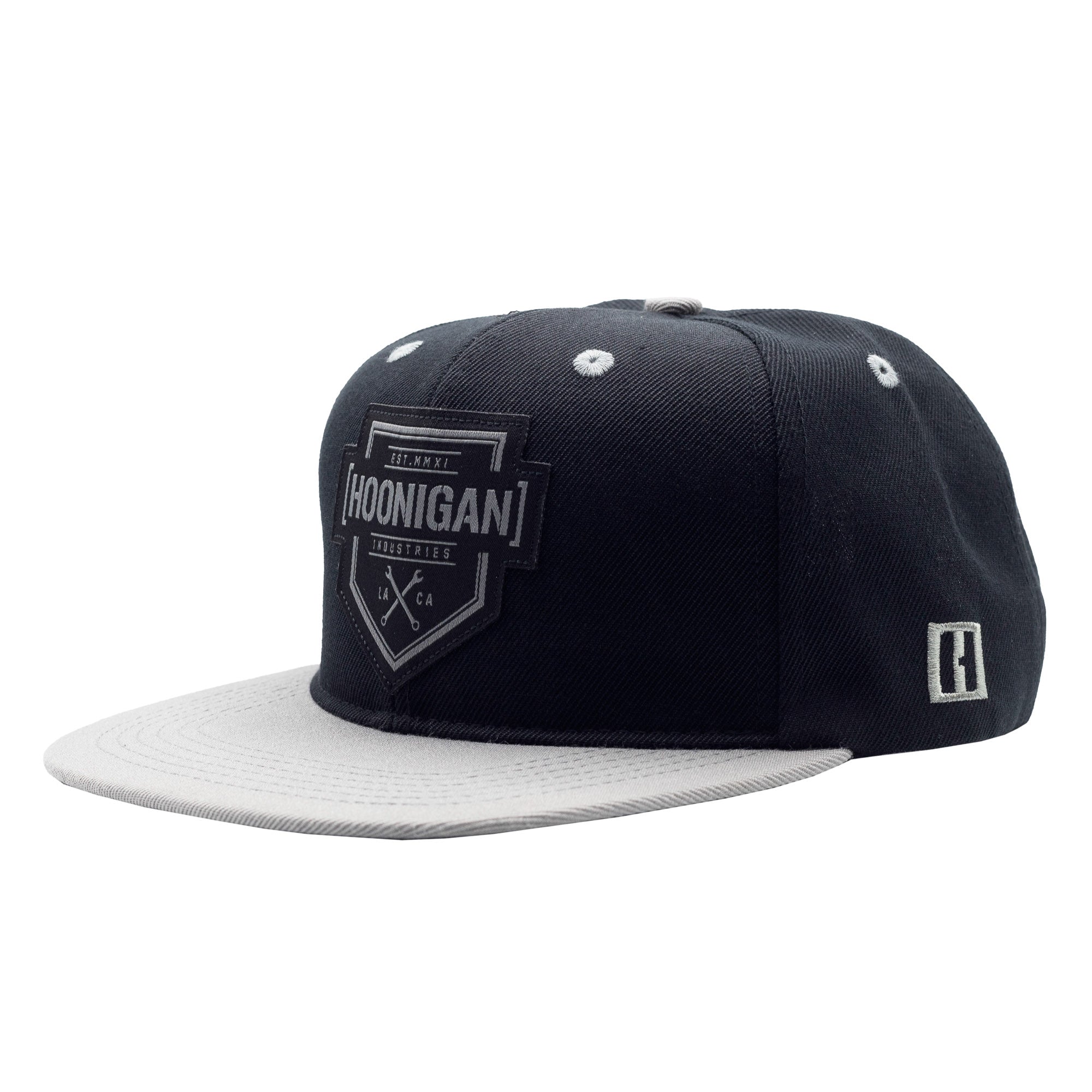 Black and white snapback hat with "Hoonigan" logo patch on front, white brim, and small logo on side, featuring a structured design.