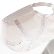 Close-up of the inside of a white unstructured strapback hat with visible stitching and ventilation eyelets.