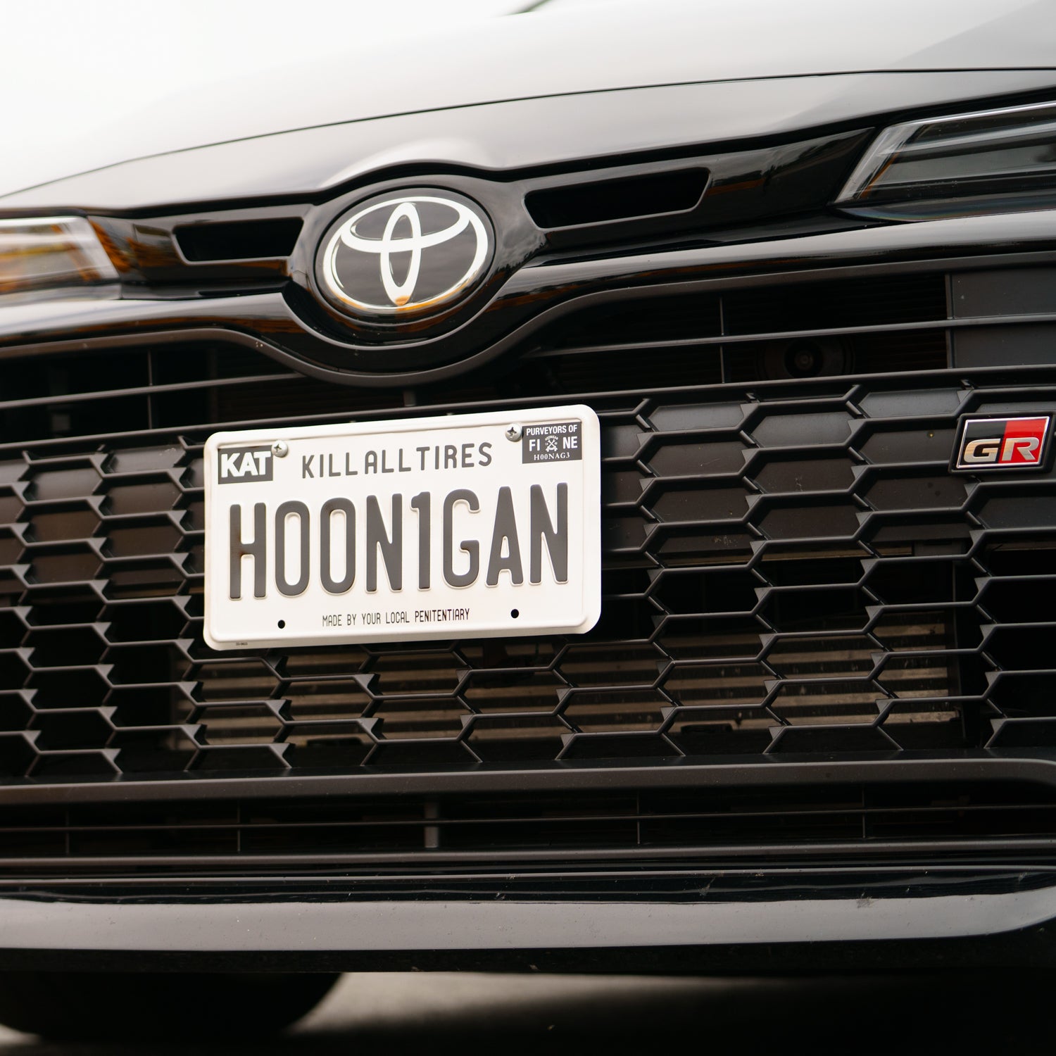 Hoonigan METAL License Plate featuring a sleek black design with the Hoonigan logo in bold white letters.