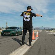 Hoonigan THIS VS THAT Short Sleeve Tee featuring bold graphics and a black colorway, displayed on a wooden surface.