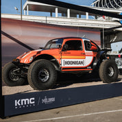 Hoonigan SCUMBUG CENSOR BAR Short Sleeve T-Shirt displayed with a modified off-road vehicle at an automotive event.
