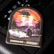 Hoonigan x Shreddy DESERT Air Freshener featuring a vibrant design of a car and helicopter against a colorful sunset backdrop.