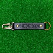 Hoonigan leather keychain featuring a bold logo and a sturdy clip, perfect for automotive enthusiasts.