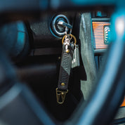 Hoonigan leather censor bar keychain hanging from a car ignition, showcasing a stylish automotive accessory.