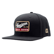 Black snapback hat featuring a Hoonigan logo patch with "Quality Mayhem" text, perfect for motorsport enthusiasts.