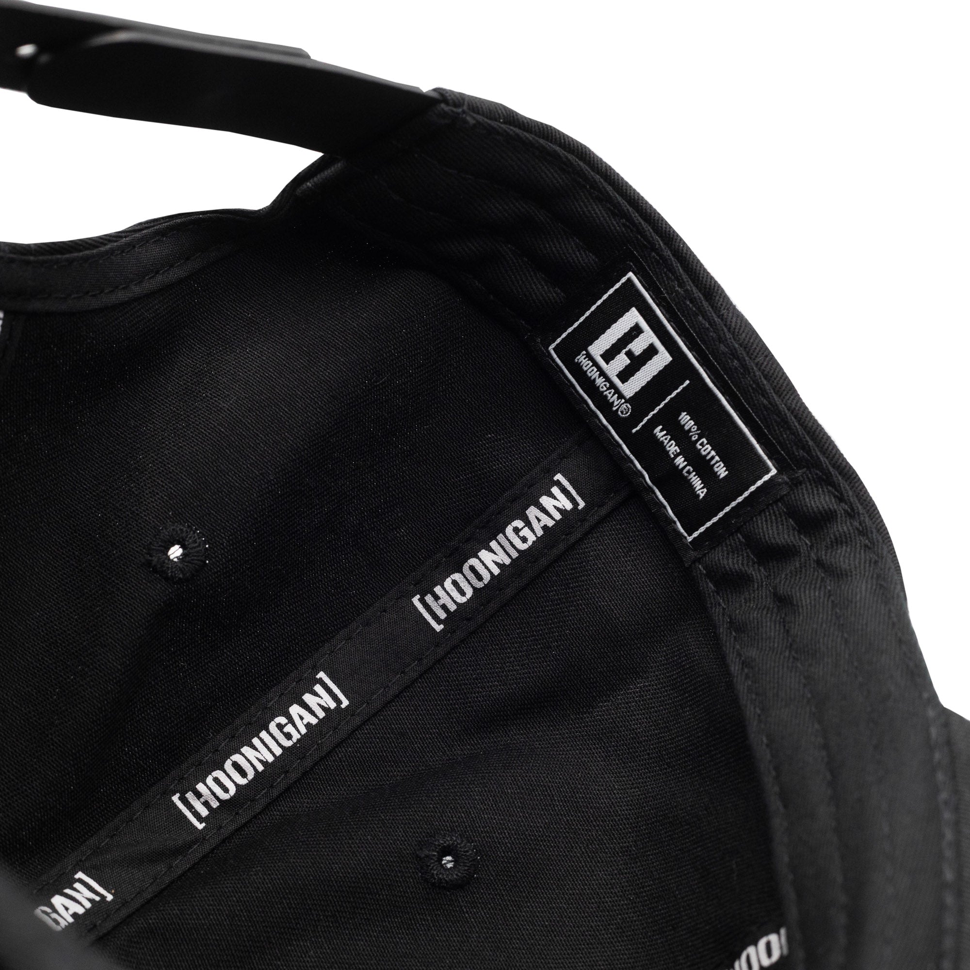 Inside view of Hoonigan RACEDAY unstructured strapback hat showcasing brand labels and black fabric lining.