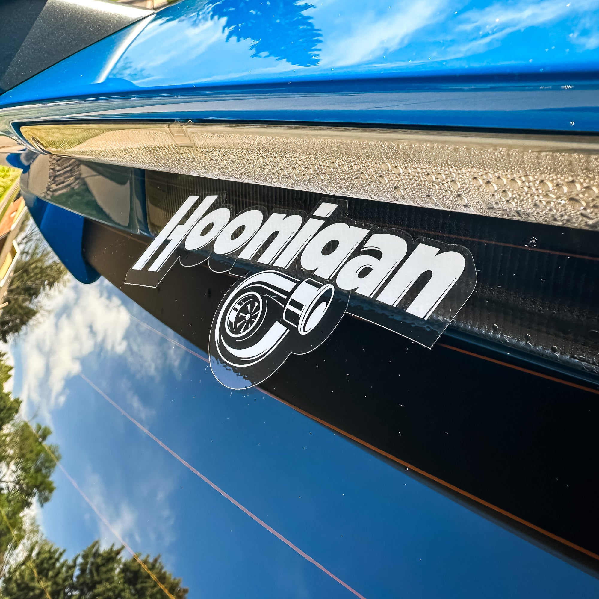 Hoonigan BOOST LEAK sticker featuring a turbocharger graphic, applied on a glossy black surface.