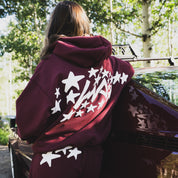 Hoonigan x Lia Block UR STAR Pullover Hoodie in burgundy, featuring a star graphic on the back, worn outdoors.