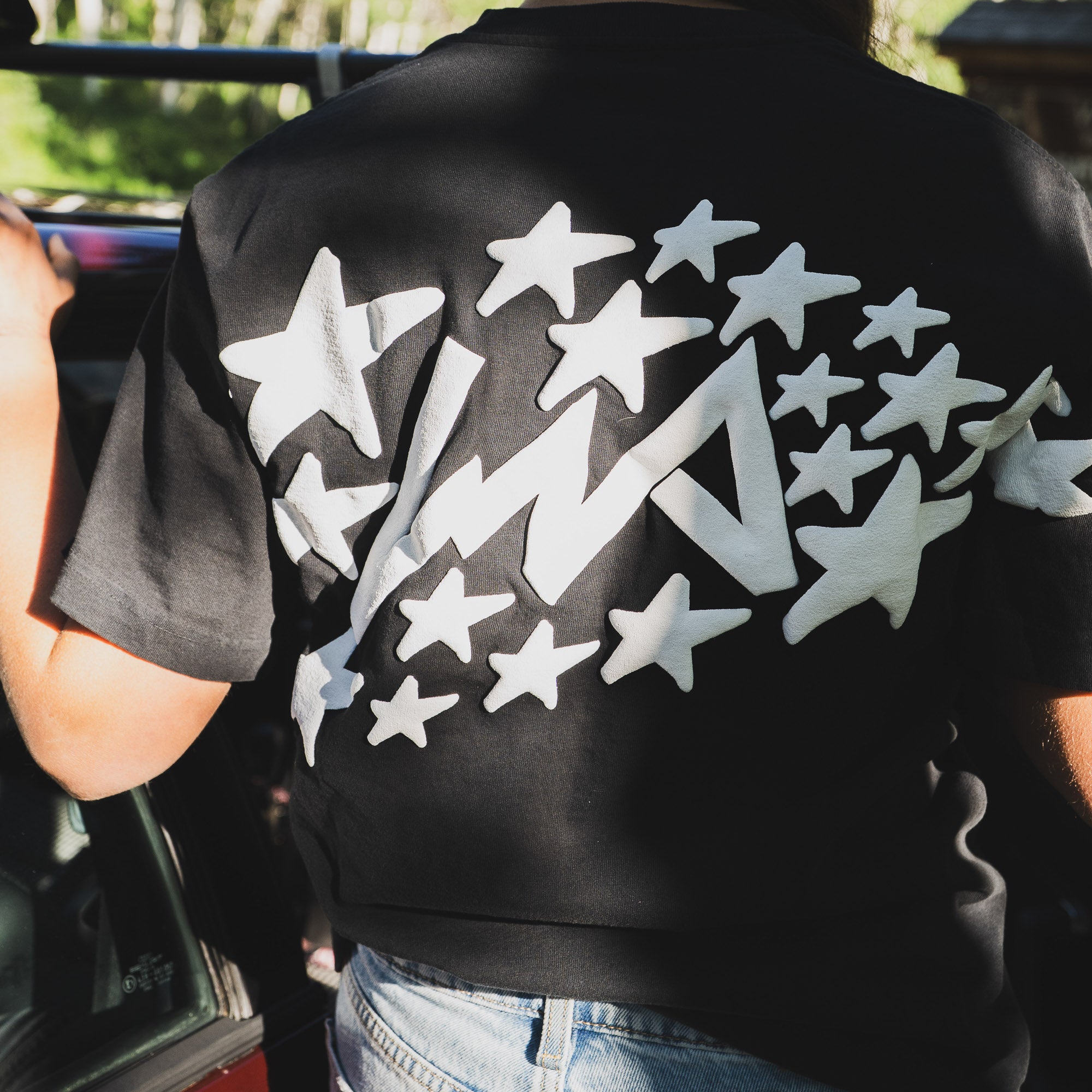 Black short sleeve t-shirt featuring a bold white star and logo design on the back, perfect for motorsport enthusiasts.