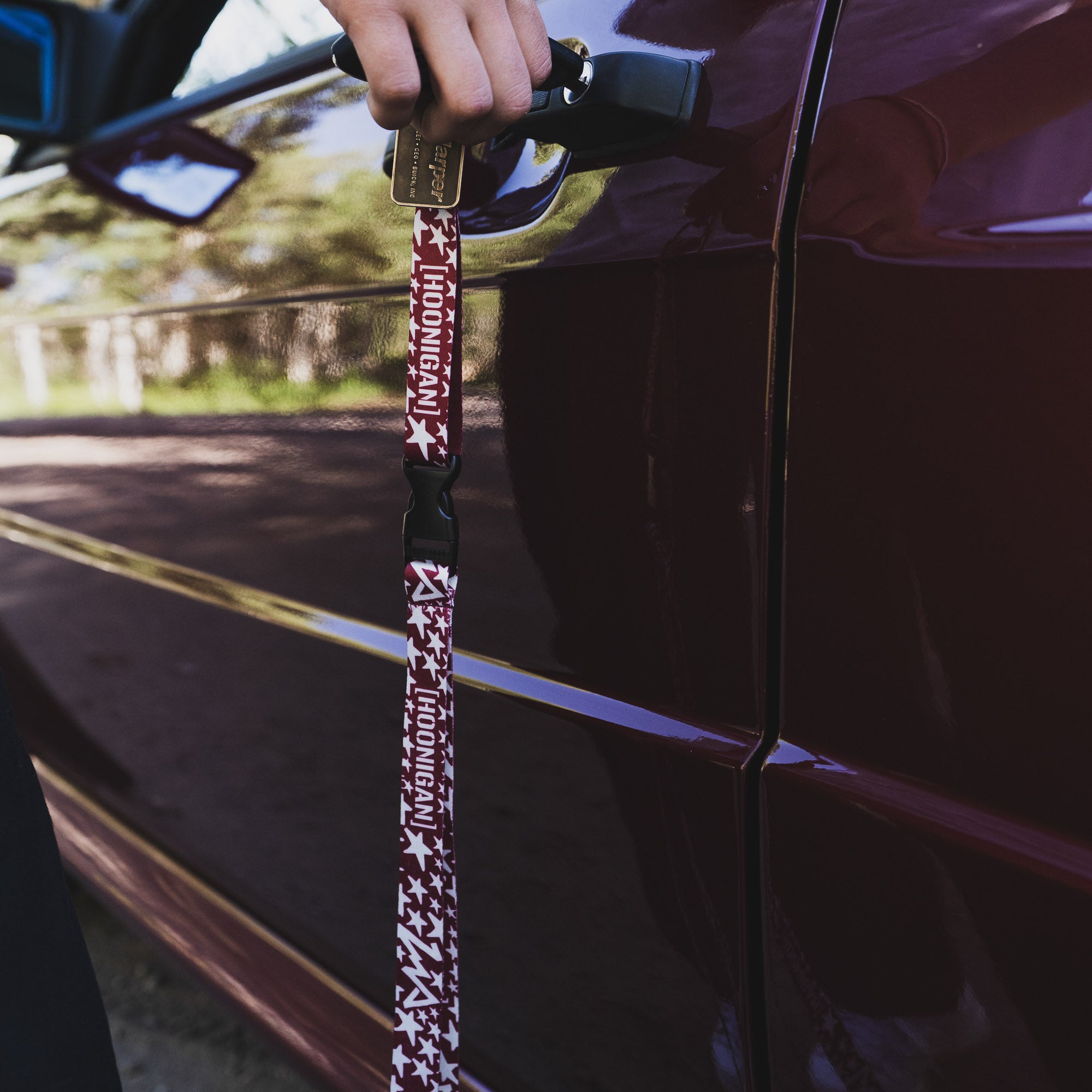Hoonigan x Lia Block UR STAR lanyard held by a person, showcasing a stylish design against a car door.