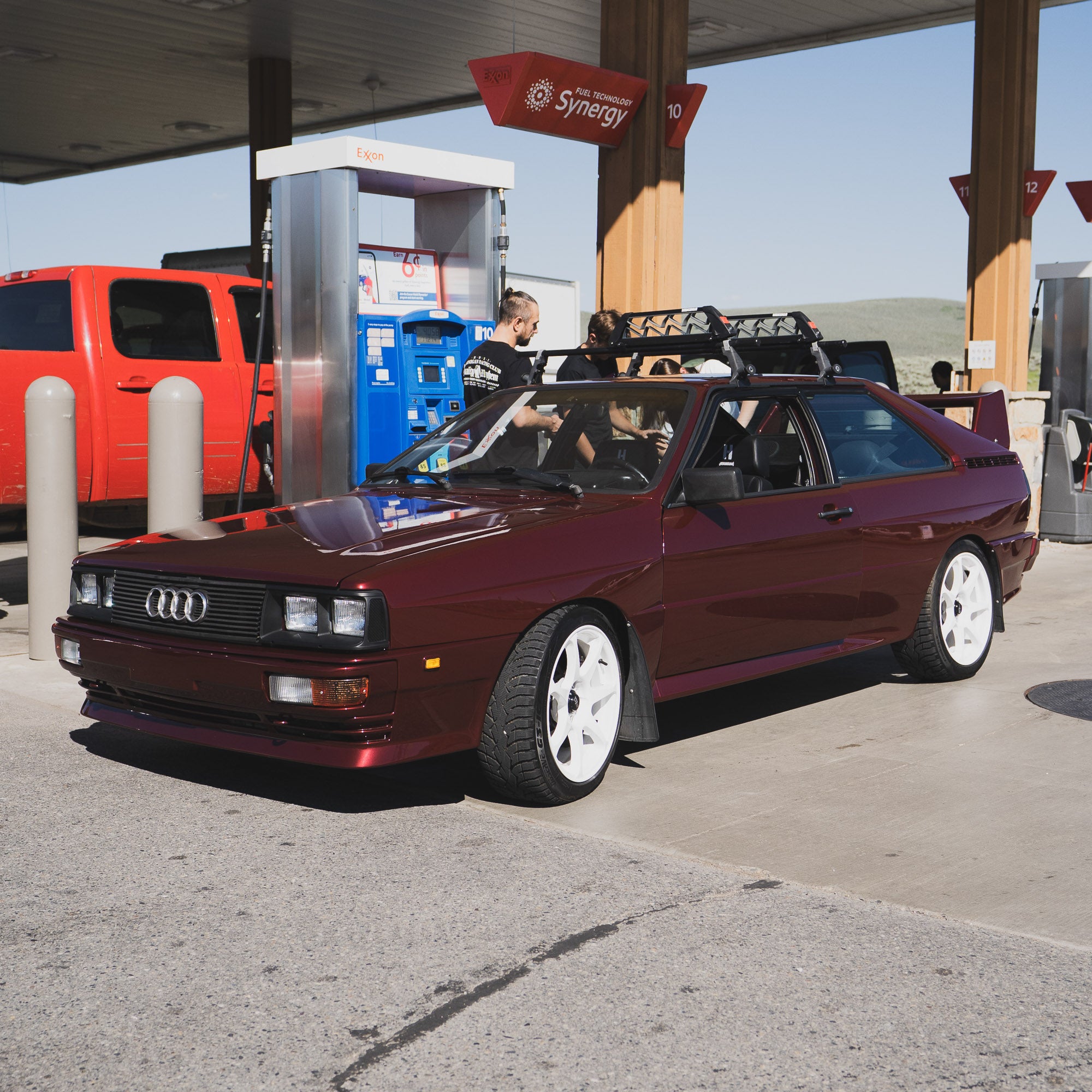 Hoonigan x Lia Block UR VINTAGE Short Sleeve T-Shirt displayed with a classic Audi at a gas station, showcasing automotive culture.