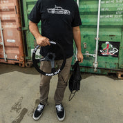 Limited edition Hoonigan FIND OUT steering wheel held by a person in a graphic tee, showcasing automotive lifestyle.