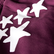 Close-up of Hoonigan x Lia Block UR STAR Sweatpants featuring bold white star graphics on a deep maroon fabric.