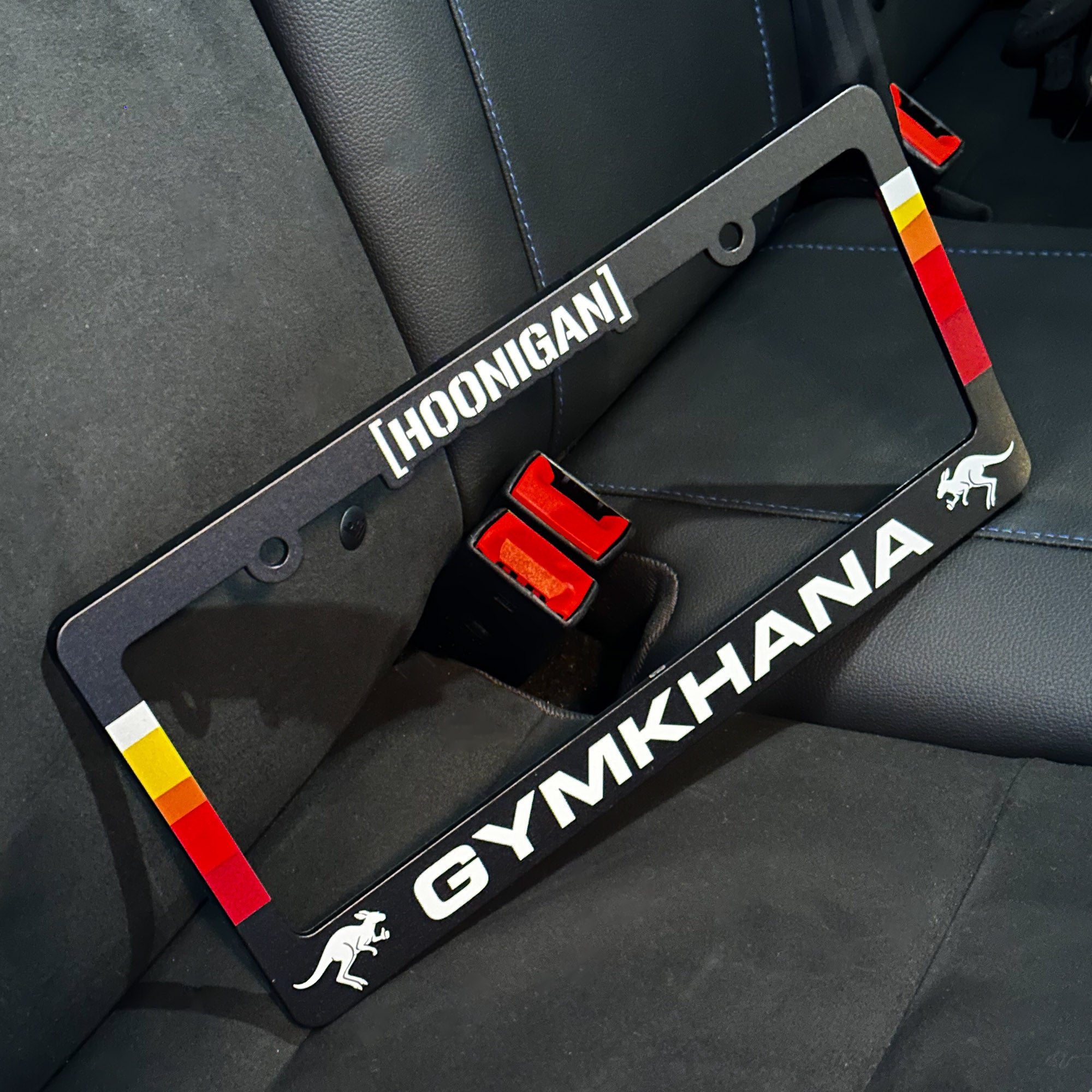 Hoonigan GYMKHANA AUSSIE SHRED LIVERY license plate frame featuring bold graphics and a sleek design for car enthusiasts.