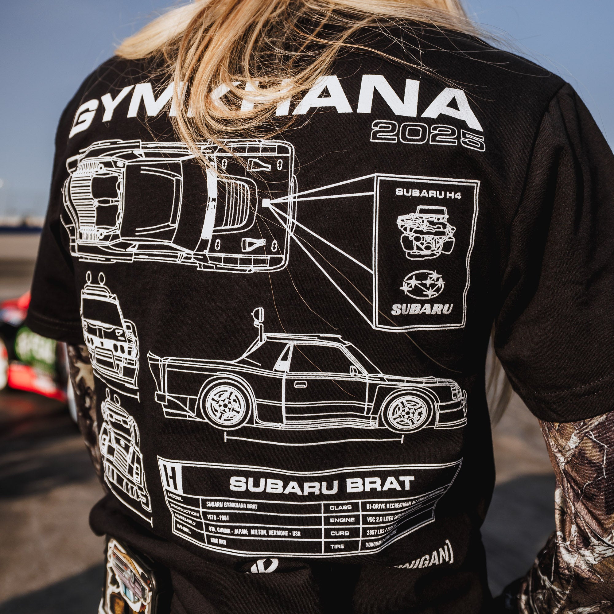 Black short sleeve t-shirt featuring detailed graphics of the Subaru Brat and GYMKHANA 2025 design on the back.