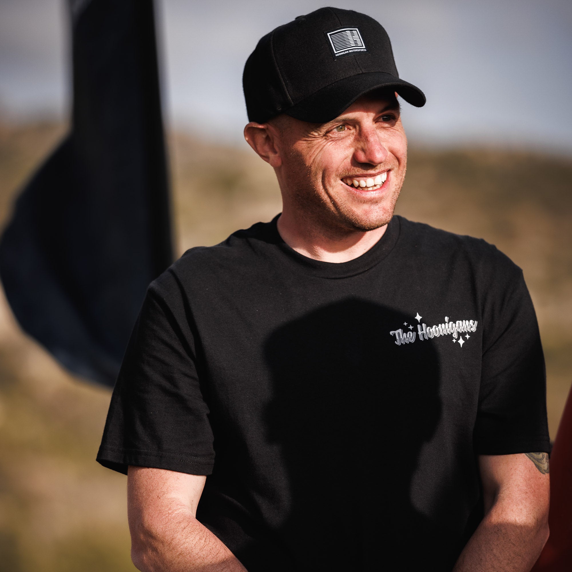 Hoonigan Motorsports snapback hat featuring a black base with a bold white logo on the front.