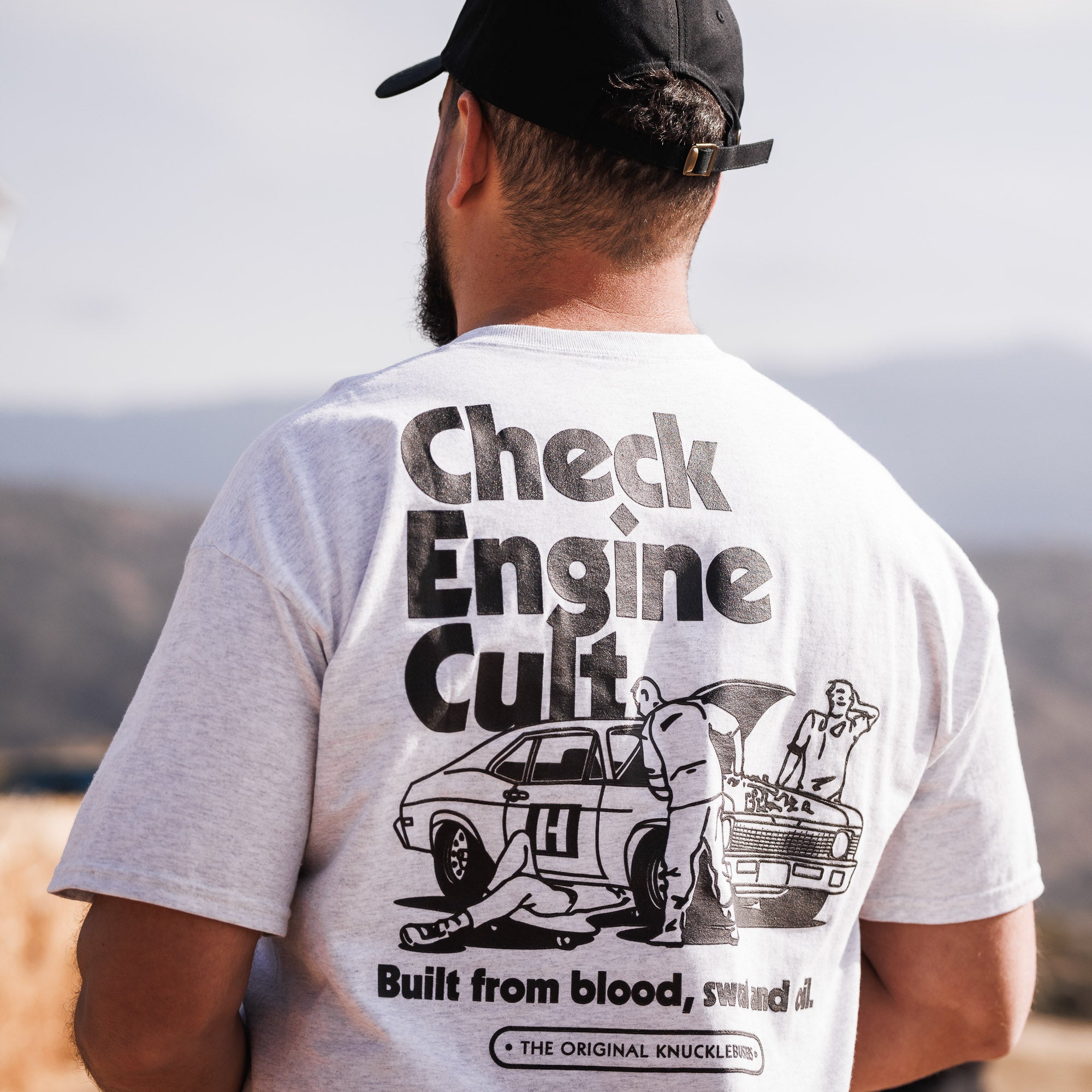 Hoonigan CHECK ENGINE CULT Short Sleeve Tee featuring a bold graphic design and vibrant colors on a black background.