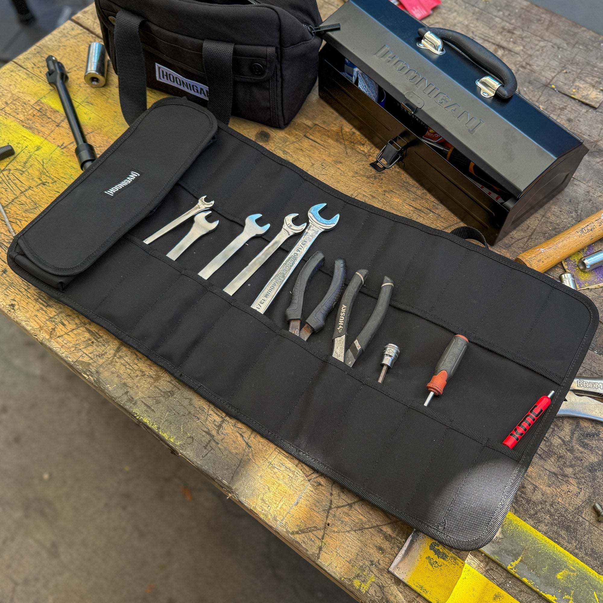 Hoonigan LIL TOOL ROLL displayed open with various tools neatly organized inside on a workbench.