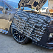Hoonigan SCATTER PRINT Fender Cover displayed on a car, protecting the fender with a bold logo design.