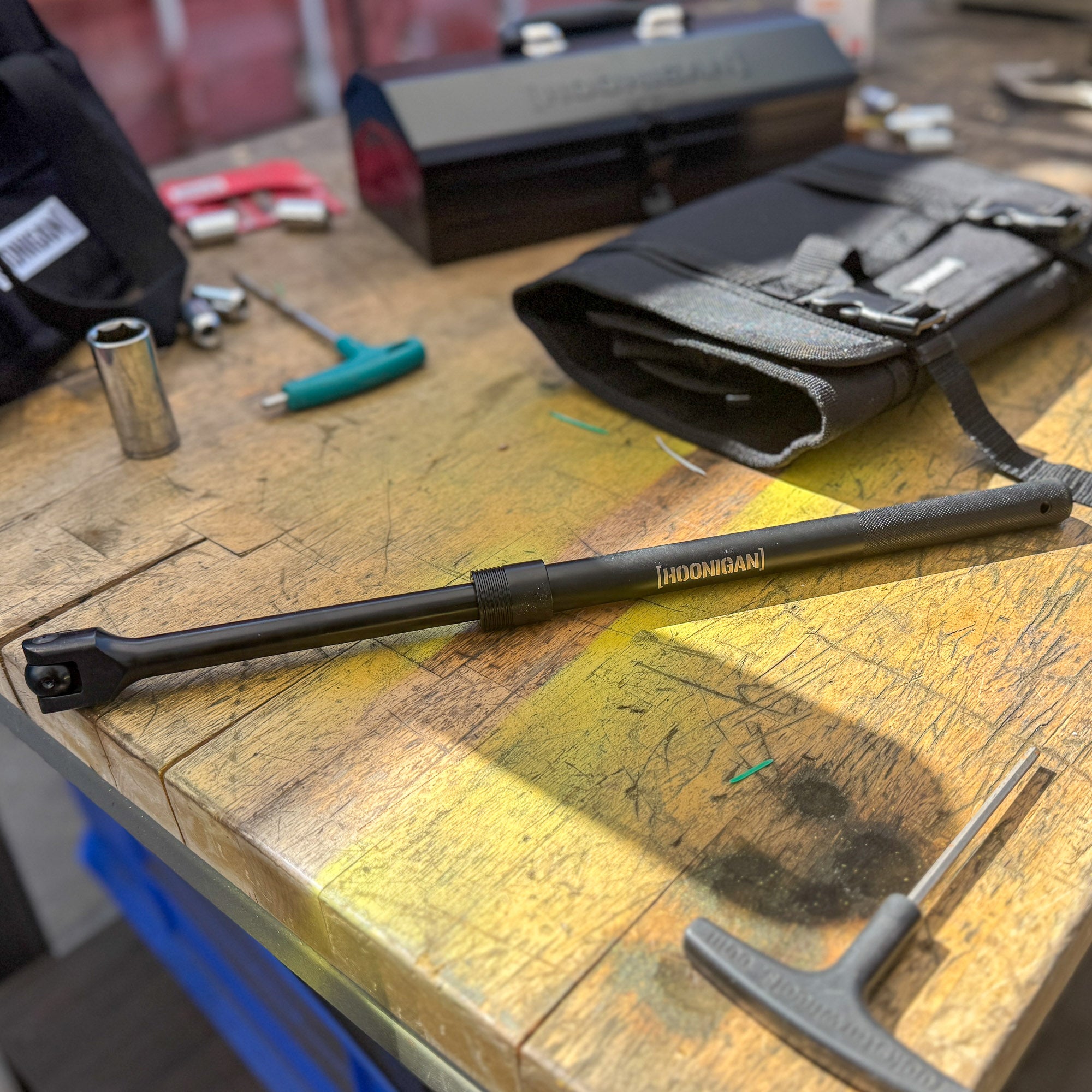 Hoonigan Adjustable BREAK IT Bar displayed on a workbench, showcasing its 18"-24" adjustable length and sturdy design.