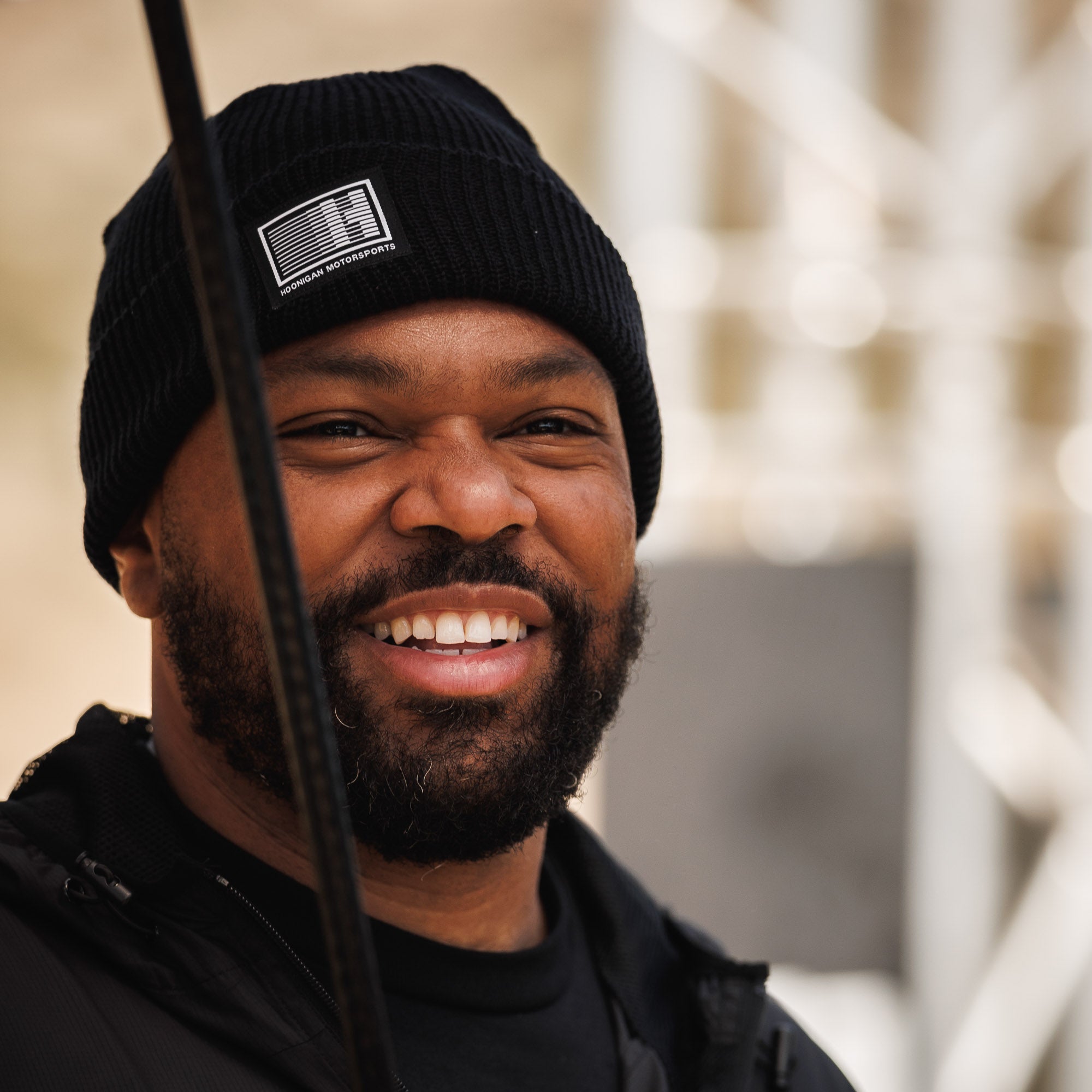 Black Hoonigan Motorsports beanie featuring a bold white logo on the front, ideal for stylish warmth in cold weather.