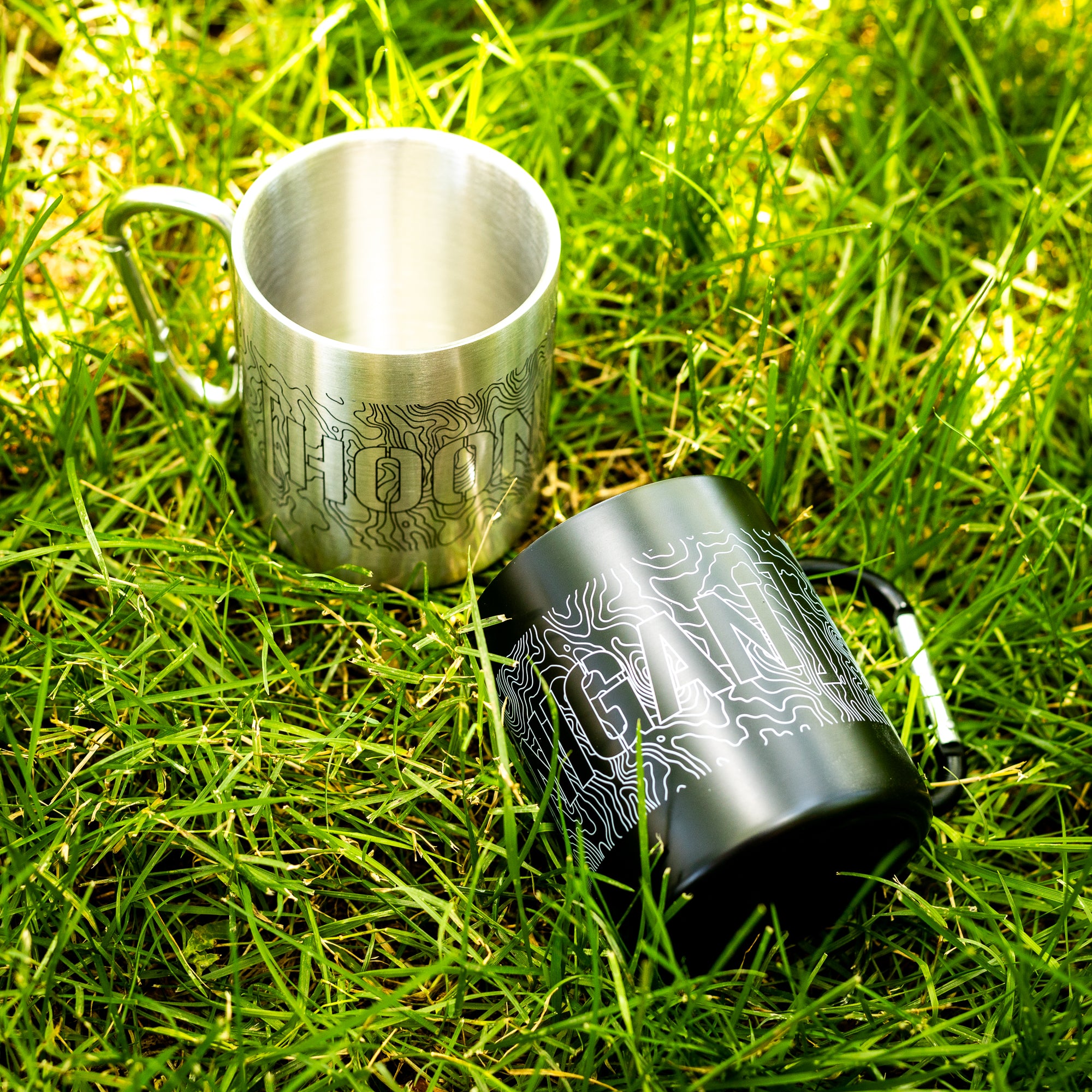 Stainless steel Carabiner Mug with topographic design and attached carabiner clip, ideal for outdoor adventures and camping.