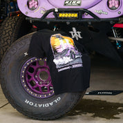 Hoonigan x Shreddy Desert Shred short sleeve t-shirt draped over a purple off-road tire in a garage setting.